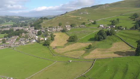 Drone-footage-reversing-and-panning-revealing-the-village-of-Settle-and-the-beautiful-North-Yorkshire-countryside-on-a-sunny-day,-including-farmland,-moorland,-allotments,-dry-stone-walls