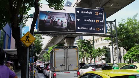 Pedestrian-Lane-sign,-billboard-LCD,-and-cars-during-a-stop-sign-along-Sukhumvit-Road-in-Bangkok,-Thailand
