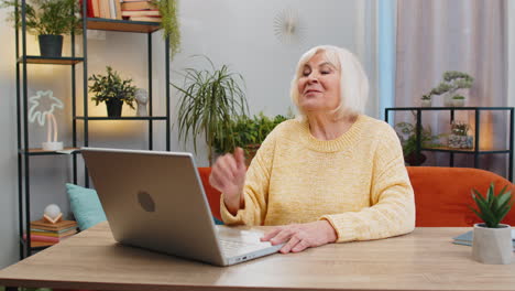 Senior-grandmother-woman-at-home-looking-at-camera-making-video-conference-call-with-friends-family