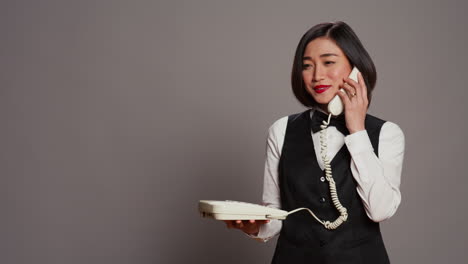 Asian-receptionist-answering-landline-phone-call-in-studio