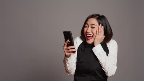 Asian-server-feeling-happy-after-reading-good-news-on-phone