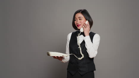 Recepcionista-Asiática-Contestando-Una-Llamada-De-Teléfono-Fijo-En-El-Estudio