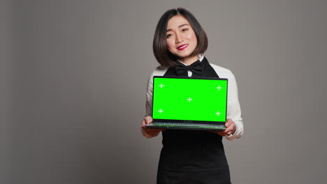 Asian-server-presenting-greenscreen-display-on-laptop-in-studio
