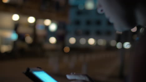 Woman-typing-on-cellphone-walking-in-night-city