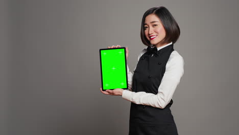 Woman-waitress-holding-tablet-with-greenscreen-display-on-camera