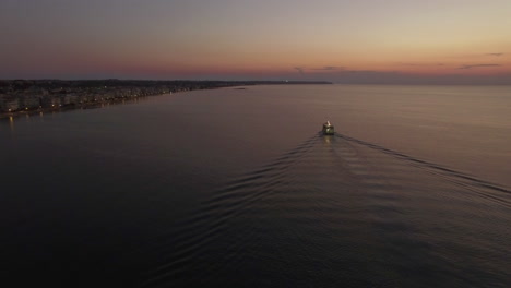 Aerial-shot-of-sailing-boat-and-distant-coast-at-night
