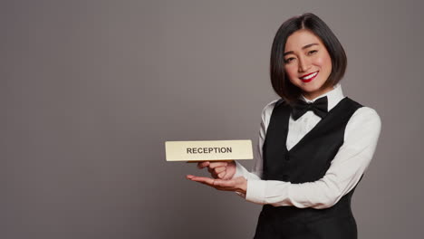 Hotel-concierge-holding-sign-to-indicate-direction-for-reception-desk