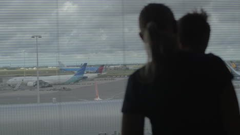 Mutter-Und-Sohn-Schauen-Durch-Das-Flughafenfenster