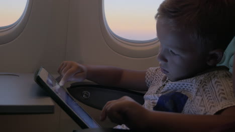 Close-up-view-of-small-boy-playing-with-touch-pad-on-the-table-in-aircraft