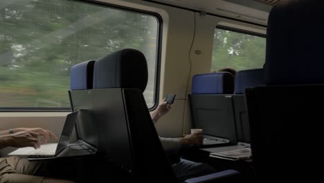 People-entertaining-with-cell-and-laptop-in-train