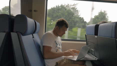 Man-using-laptop-during-ride-in-commuter-train