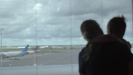 Kind-Und-Mutter-Schauen-Durch-Das-Fenster-Auf-Flugzeuge