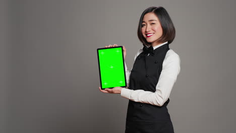 Asian-restaurant-hostess-showing-greenscreen-display-in-studio