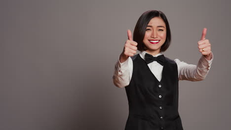 Asian-reception-staff-doing-thumbs-up-symbol-on-camera