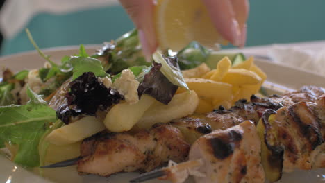 Close-up-view-of-meal-on-the-plate-that-woman-waters-lemon-juice-potatoes-salad-and-chicken-barbecue
