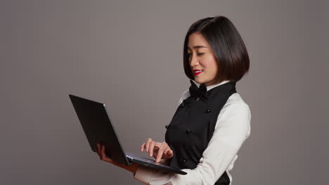 Asiatische-Kellnerin-überprüft-Alle-Tischreservierungen-Online-Auf-Dem-Laptop