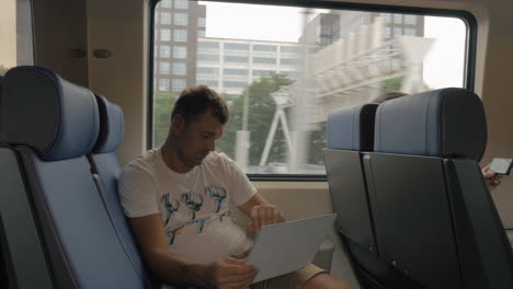 Man-in-train-entertaining-with-laptop