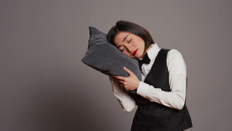 Asian-front-desk-staff-falling-asleep-with-pillow-in-hand