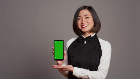 Restaurant-hostess-presenting-smartphone-with-greenscreen