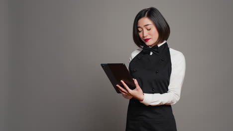 Asian-restaurant-server-checking-all-table-reservations-on-tablet