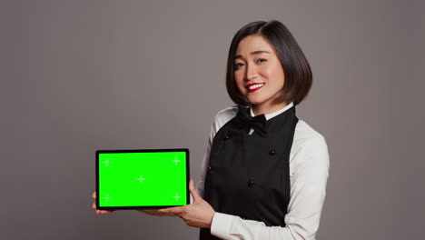 Woman-waitress-holding-tablet-with-greenscreen-display-on-camera
