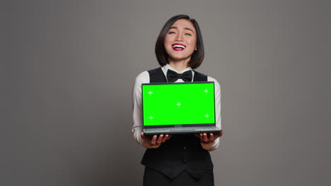 Asian-hotel-concierge-holding-pc-with-greenscreen-on-camera