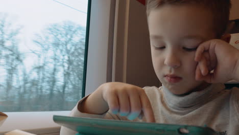 Child-playing-on-touch-pad-during-train-ride