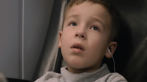Boy-watching-TV-in-train-he-listening-audio-with-earphones