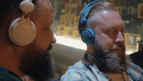 Close-up-view-of-two-bearded-men-listening-musics-using-colorful-on-ear-headset