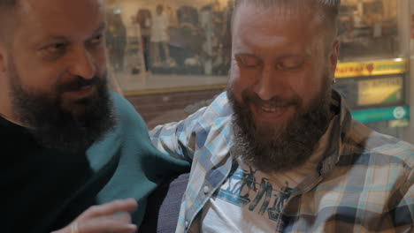 Close-up-view-of-two-white-mature-bearded-men-using-smartphone-together