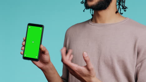 Happy-man-pointing-towards-green-screen-mobile-phone,-showing-thumbs-up-sign