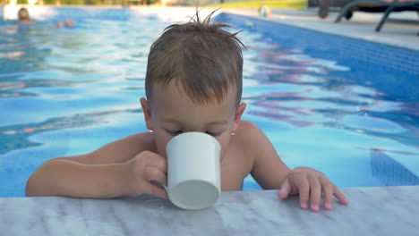 Little-child-drinking-water-in-the-swimming-pool