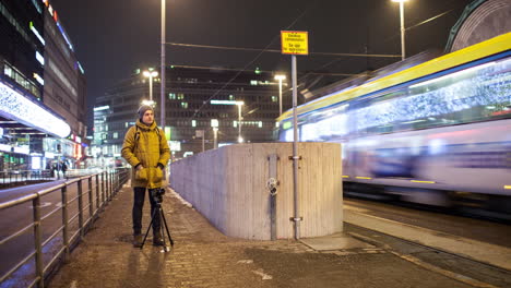 Timelapse-of-man-shooting-video-in-night-Helsinki-with-transport-traffic