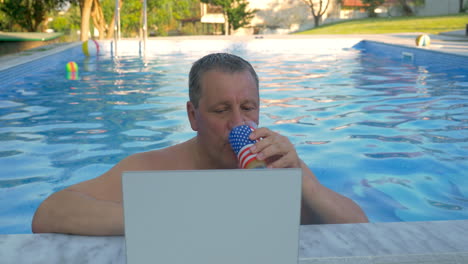 Smiling-Man-in-Home-Pool-with-Laptop