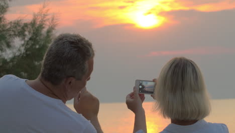 Menschen-Fotografieren-Den-Sonnenuntergang-Am-Meer-Mit-Smartphones