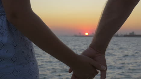 Young-couple-holding-hands-at-sunset