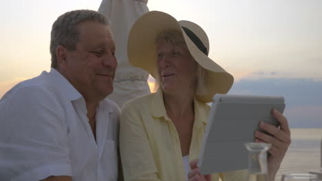 Mature-Couple-Watching-Photos-in-Tablet-and-Laughing