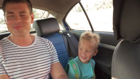 Cheerful-father-and-son-traveling-by-car