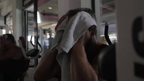 Tired-man-wiping-sweat-after-workout-in-the-gym