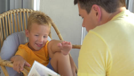 Lächelnder-Junge,-Der-Seinem-Vater-Beim-Lesen-Eines-Buches-Zuhört