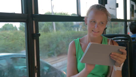 Smiling-woman-communicating-on-pad-in-the-bus
