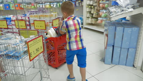 Kleiner-Junge-Rollt-Einkaufswagen-Im-Supermarkt