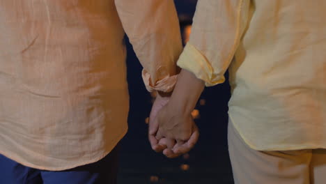 Close-up-of-man-and-woman-holding-hands-at-sea