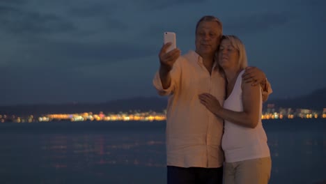 Senior-couple-on-vacation-taking-cell-selfie-at-night