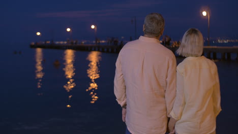 Loving-senior-couple-on-water-front-at-night