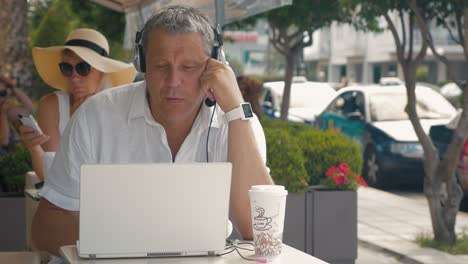 Mann-Mit-Headset-Unterhält-Sich-Im-Straßencafé-Per-Video