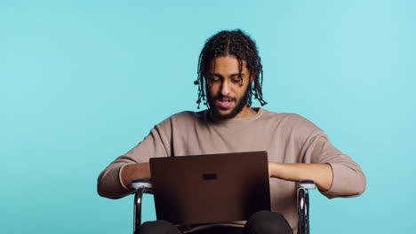 Man-in-wheelchair-chatting-with-friend-over-internet-videocall-using-laptop