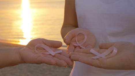 Women-with-pink-awareness-ribbons-outdoor-at-sunset