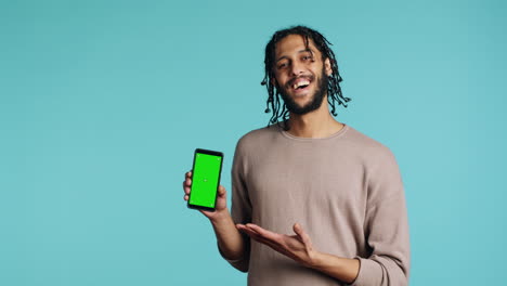 Happy-man-pointing-towards-green-screen-mobile-phone,-showing-thumbs-up-sign