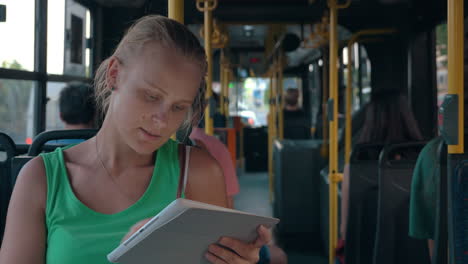 Young-woman-entertaining-with-pad-during-bus-ride